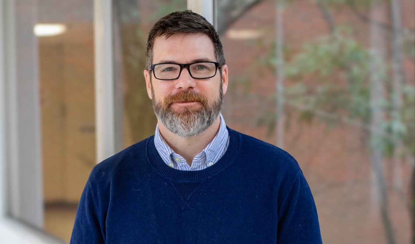 A portrait photo of Jesse Schank standing outside a building.