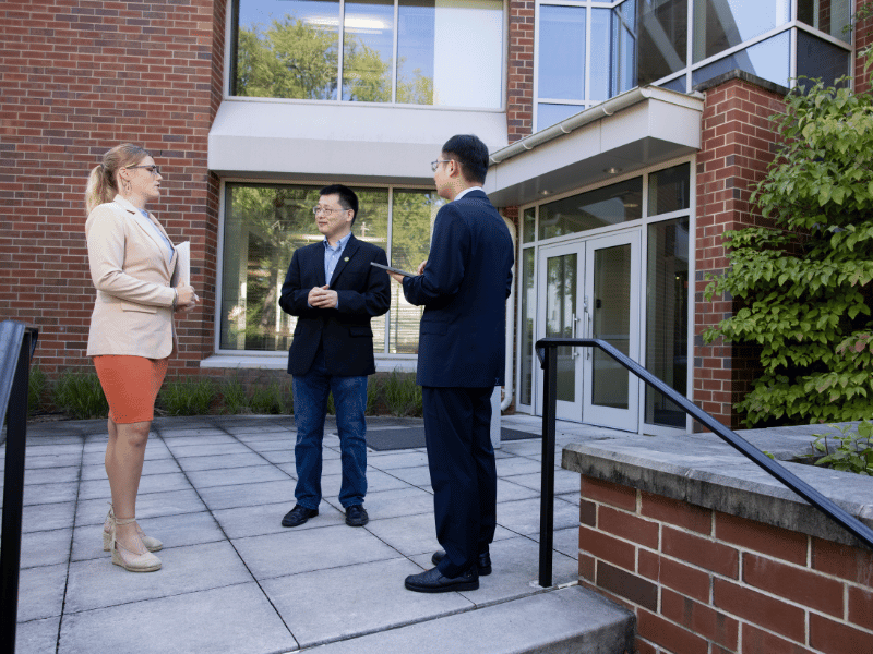 (L-R) Graduate student Carey Tyler talks with professor Zhuo (Adam) Chen and visiting PhD student Gang Li in front of Wright Hall on the Health Sciences Campus.