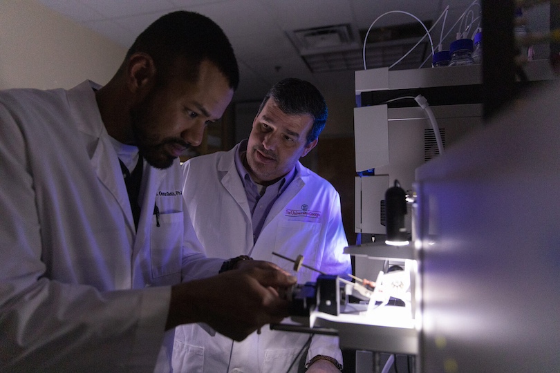 (L-R) Graduate student Osman Sheikh interacts with professor Lance Wells at a mass spectrometer in Wells’ laboratory.