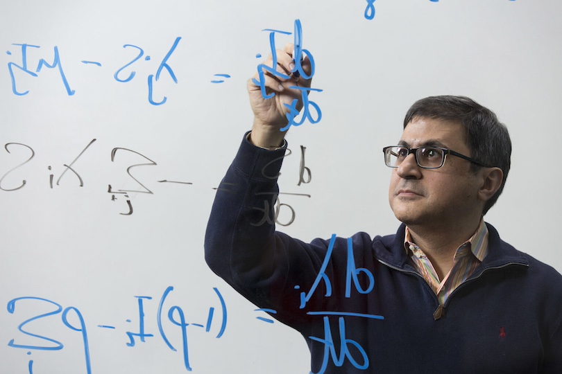 Professor Pejman Rohani works on equations on the board inside the Ecology building.