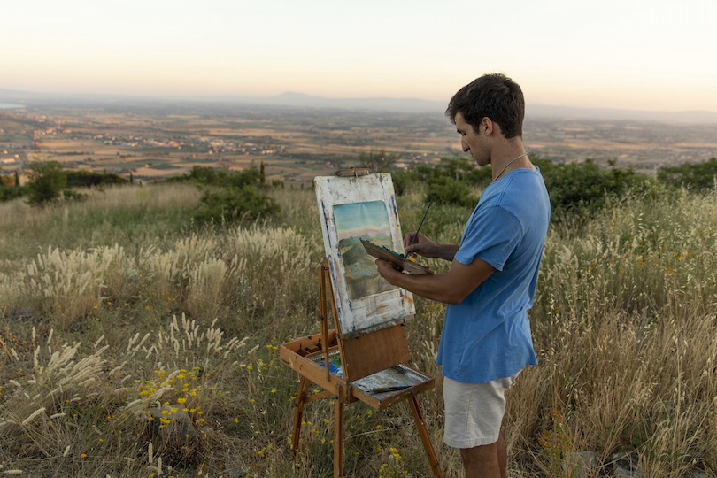 Undergraduate Cole Muzio paints a landscape as sunset approaches on a ridge in Cortona, Italy overlooking the Tuscany countryside.