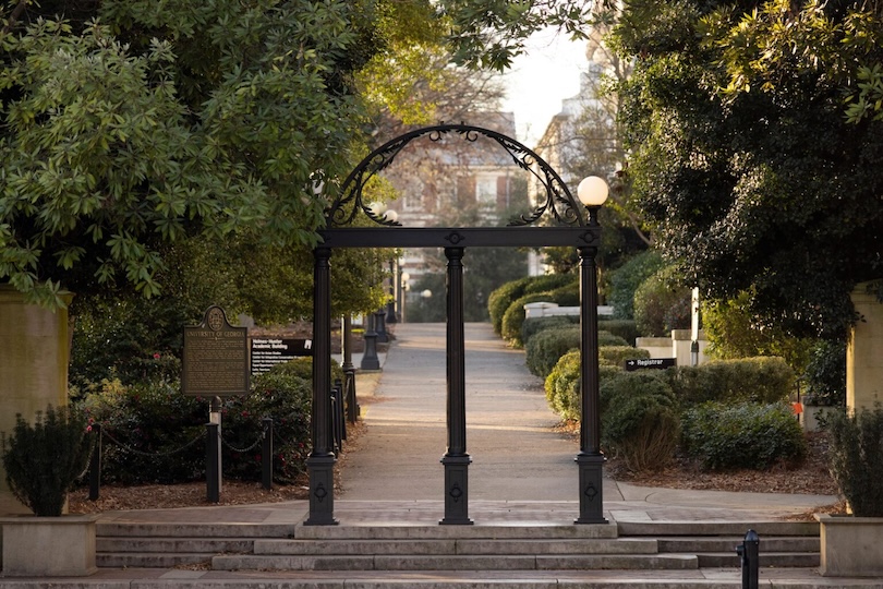 The Arch is highlighted by early morning sunlight with the UGA Historic Marker and North Campus in the background.