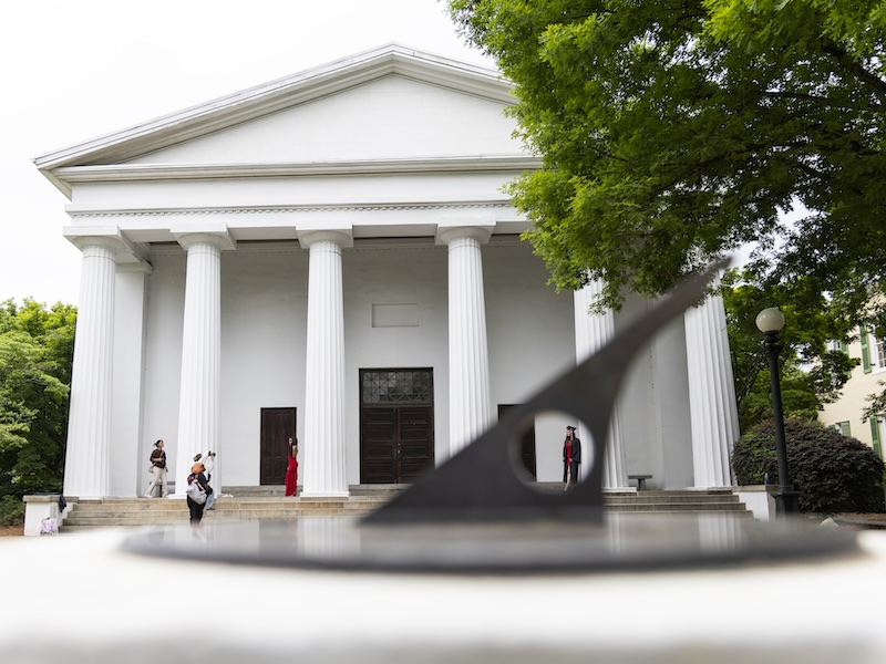 A student framed by the North Campus Sundial while taking graduation photos at the Chapel before the spring commencement ceremonies.