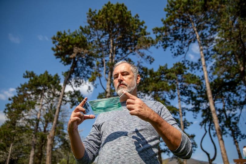 Mature Man Putting On Protective Mask Outdoors in Nature.