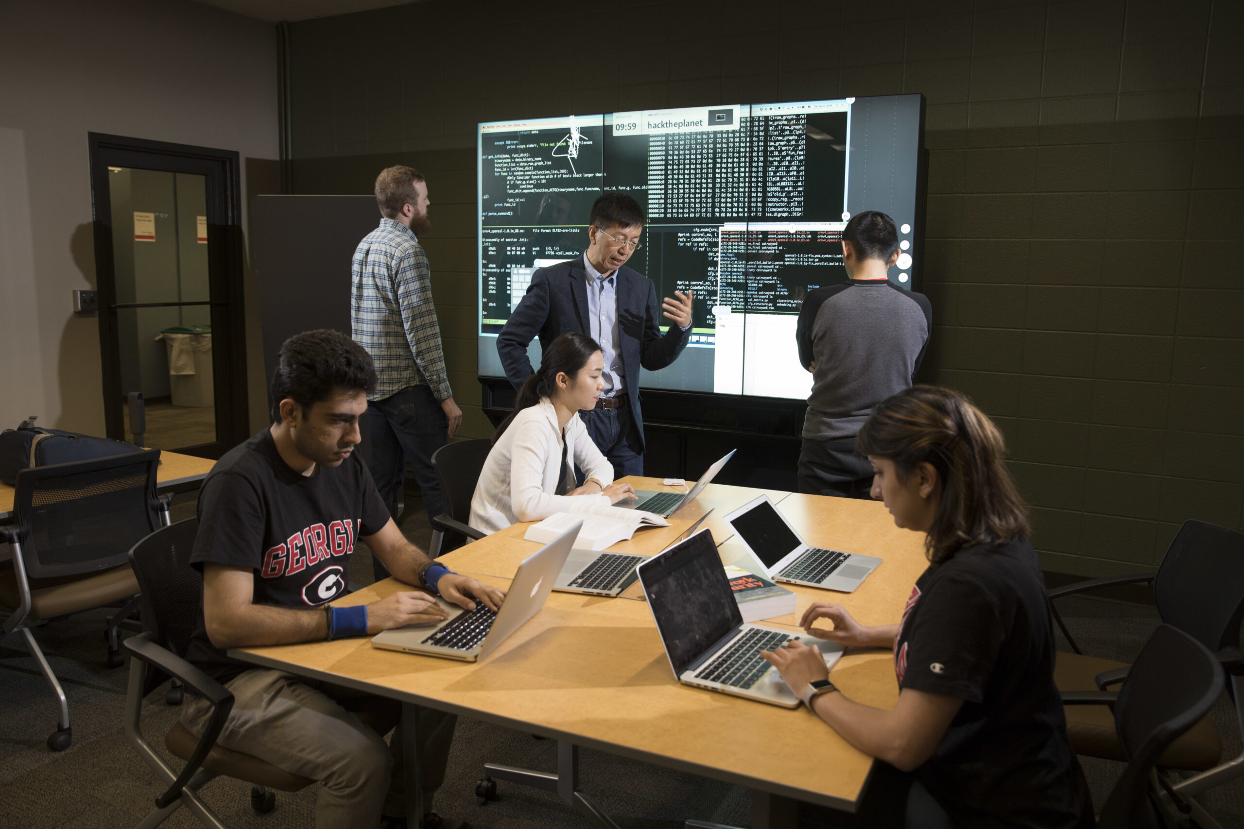 A professor working with students in an AI classroom.