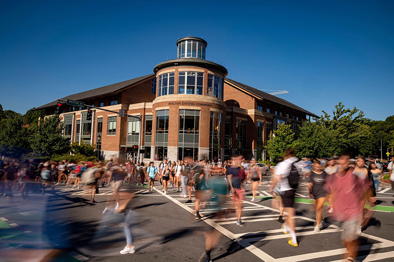 Crowds of students walk across the intersection crosswalks in front of Bolton Dining Commons.